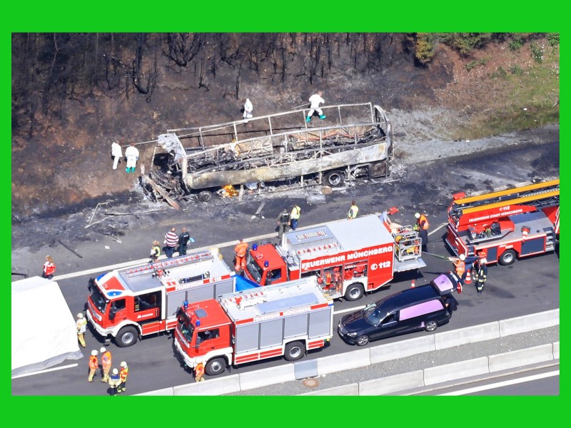 Der komplett ausgebrannte Bus, daneben Feuerwehr- und Rettungswagen sowie Leichenwagen. 