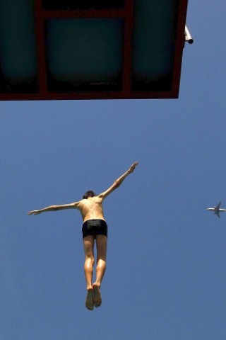 Warum in die Ferne fliegen, wenn es gerade hier so schön ist? Dieser Freibadbesucher in Düsseldorf springt in das kühle Nass.