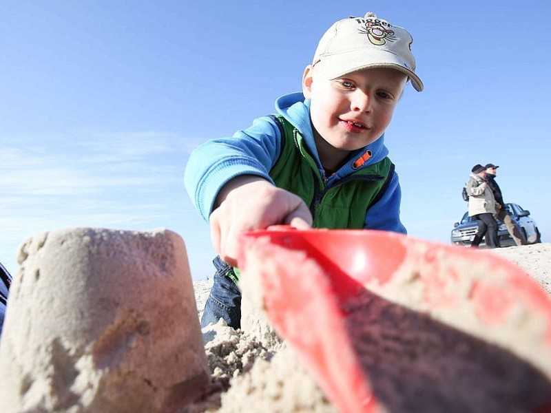 Der vierjährige Niklas aus Bern baut am 09.03.2014 bei Sonnenschein am Strand in St. Peter Ording eine Sandburg.