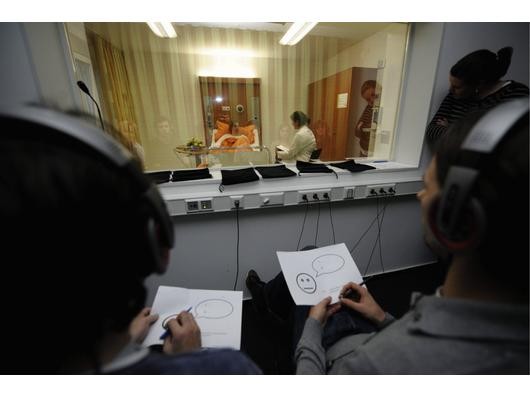 Kommilitonen verfolgen im Studienhospital in Münster hinter einer verspiegelten Scheibe ein Patientengespräch zwischen einer Studentin (hinten rechts) und einer Schauspielerin (hinten links). Foto: ddp