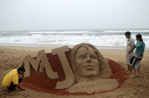 Der indische Sandkünstler Sudarsan Pattnaik (l) fertigt eine Skulptur am Strand von Puri an.