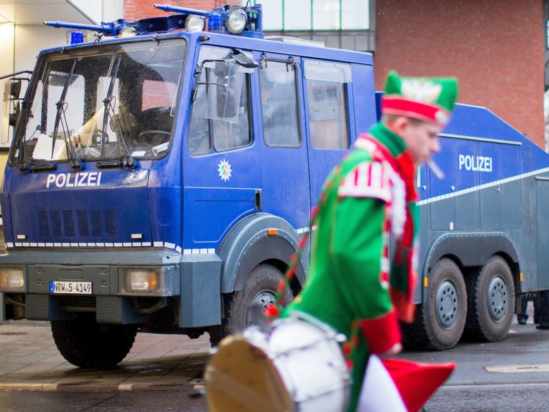 Ein Musiker einer Garde passiert einen Wasserwerfer der Polizei vor dem Alter Markt in Köln.