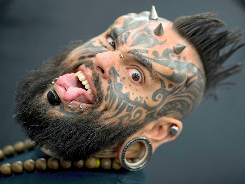 Der spanisch-venezolanische Body-Künstler und Tätowierer Emilio Gonzalez zeigte sich bei der 25. Ausgabe der „Tattoo Convention“. Dabei sind die Metallkegel auf seiner Stirn auf Gewindeschrauben unter der Haut fixiert, während Silikonimplantate dem Gesicht einen eigenen Ausdruck verleihen. Auch die Zunge hat sich der Mann spalten lassen. 