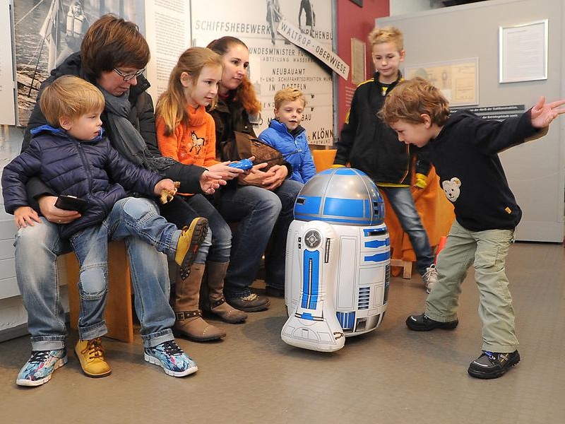 Kinder spielen mit dem ferngesteuerten R2D2.