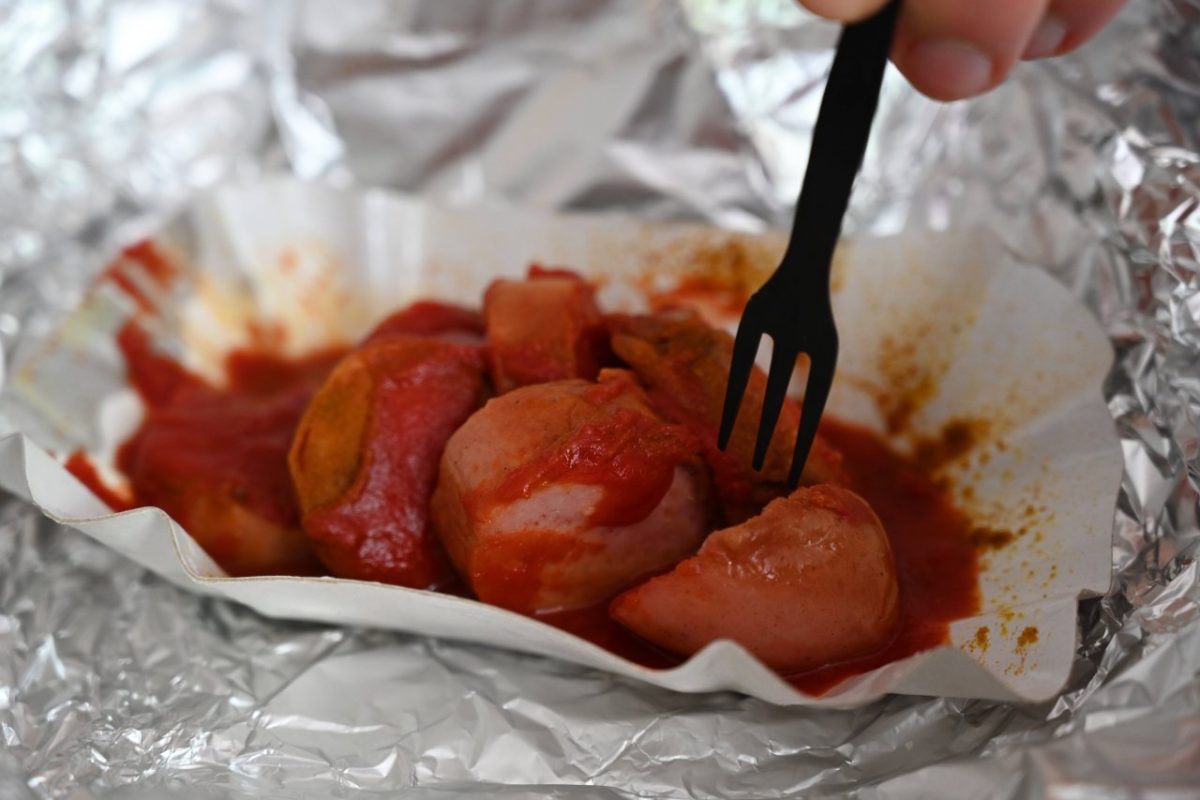 Eine Currywurst mit Pommes in einer Schale.