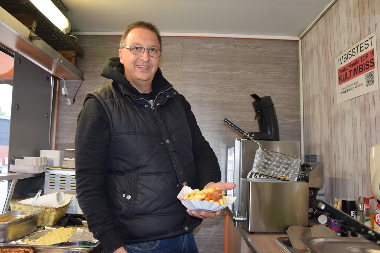 Marco Peters bietet Currywurst am Stiel. 