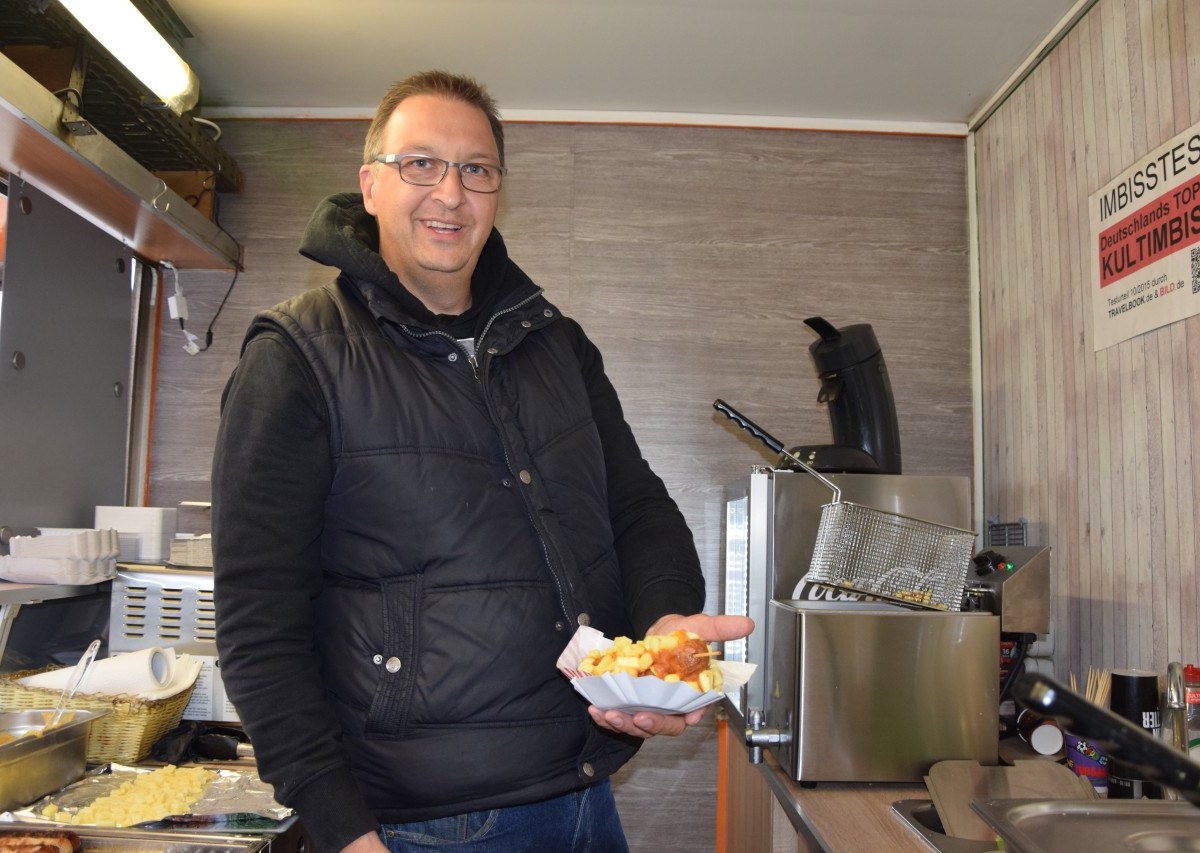 Marco Peters bietet Currywurst am Stiel.