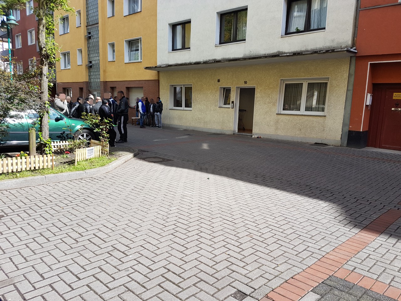 Misstrauische Blicke und eisernes Schweigen: Vor dem Haus des erstochenen Jungen (14) an der Henriettenstraße sammeln sich am Dienstagmorgen Dutzende Männer.