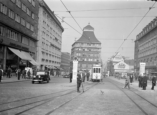 Schienenreiniger an der Haltestelle Essen Hauptbahnhof, 1938. Heute ist hier der Willy-Brandt-Platz. Rechts ist der Handeshof zu erkennen, links das damalige Defaka-Kaufhaus, heute der Kaufhof. Das Eick-Haus in der Bildmitte, eine Schöpfung des Margarethenhöhe-Architekten Georg Metzendorf, hatte noch sein eigenwilliges Pagadodendach. Es fiel dem Bombenkrieg zum Opfer. Heute residiert hier das Modehaus Ansons.