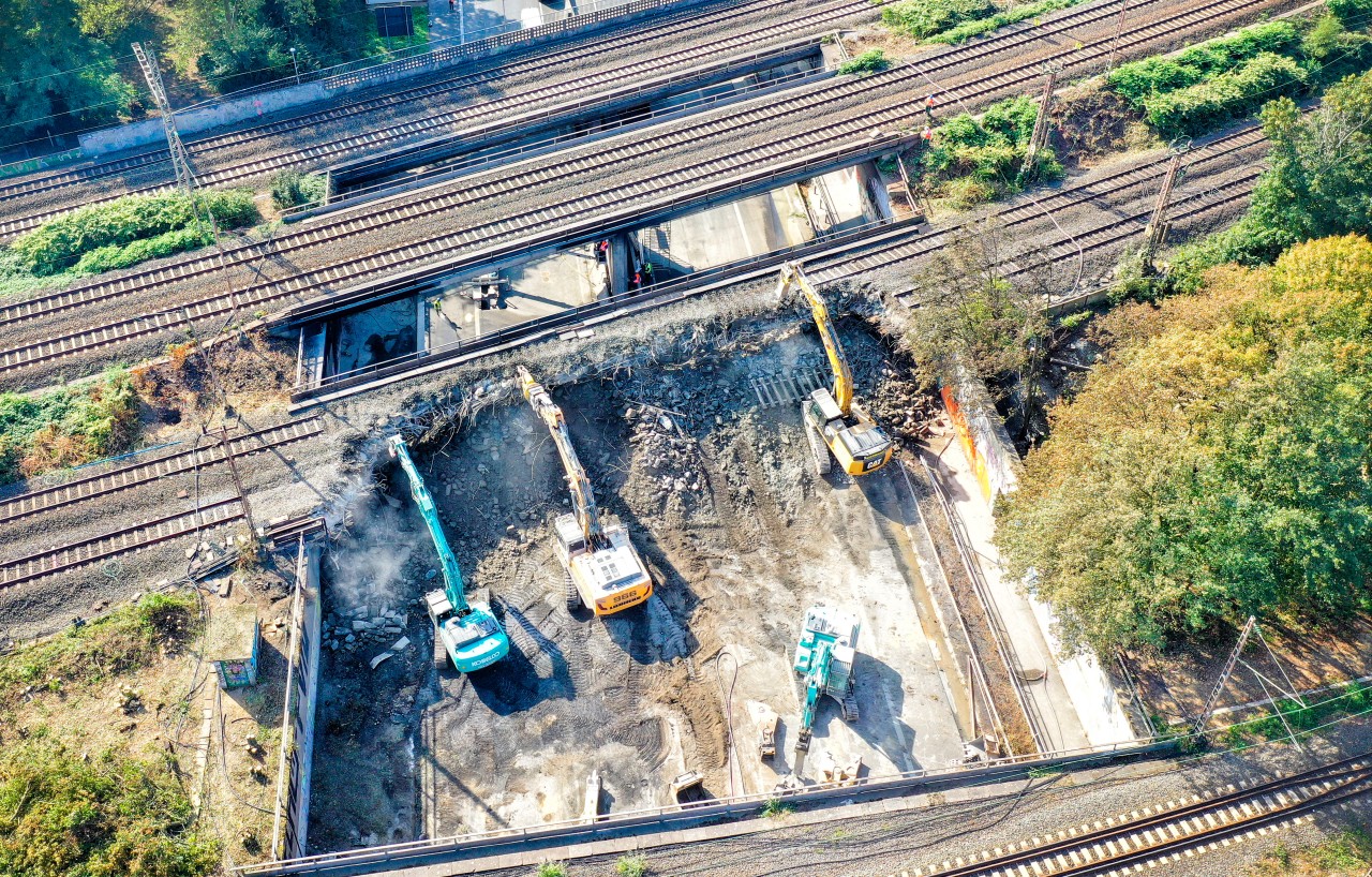 Bagger reißen die durch Feuer beschädigte Eisenbahnbrücke über die Autobahn 40 ab.