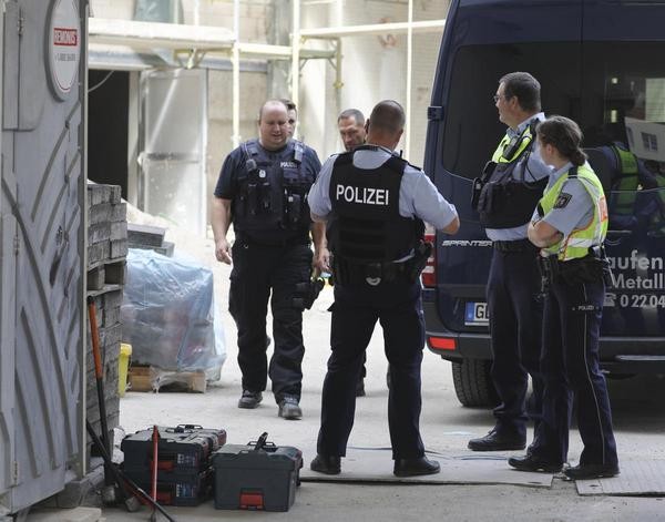 Polizisten stehen vor dem Hintereingang eines Wohngebäudes in der Innenstadt.