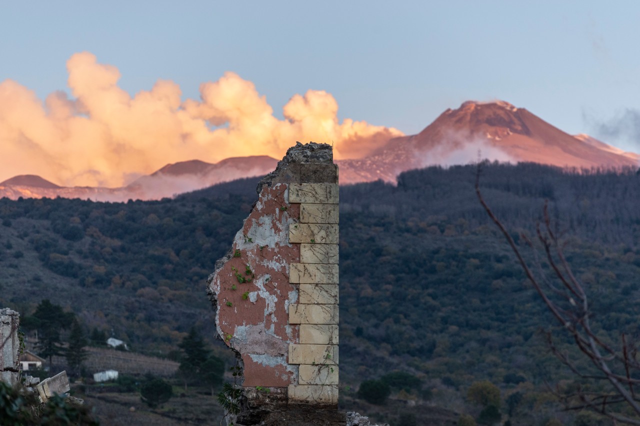  Hinter den Überresten eines eingestürzten Gebäudes steigen Rauchfahnen auf aus dem Vulkan Ätna in Fleri, Sizilien. Ein Erdbeben, das durch den italienischen Vulkan Ätna ausgelöst wurde, hat Ostsizilien im Dezember erschüttert. 