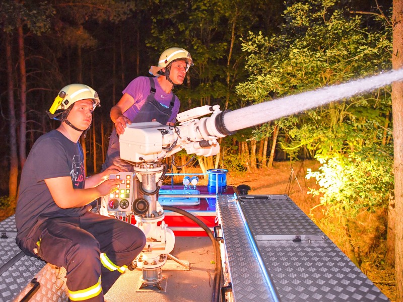 Mitglieder der Freiwilligen Feuerwehr Schlieben löschen mit einer Wasserspritze auf dem Dach ihres Fahrzeuges den Waldbrand nahe Klausdorf.