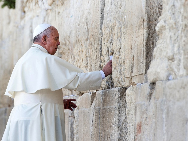 Papst Franziskus bei seinem Besuch der Klagemauer im Mai 2014. Das Foto zeigt ihn, wie er ein Bittgesuch um Frieden in die Ritzen des Bauwerks steckt. Das machen auch viele andere Gläubige. 