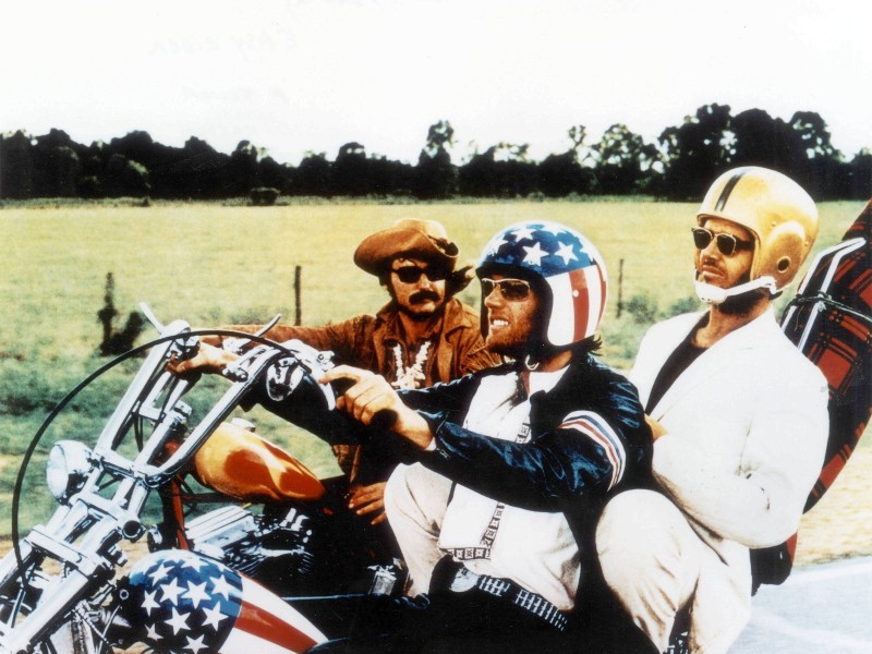 Seinen Durchbruch feierte Nicholson (Mitte) als alkoholsüchtiger Rechtsanwalt George Hanson in dem Road-Movie „Easy Rider“ (1969). Der Film mit Henry Fonda (r.) und Dennis Hopper (l.) als Motorradfahrer auf der Suche nach Freiheit, Drogen und Sex wurde zum Kult. Bis sie am bitterbösen Ende im Straßengraben landen, abgeknallt von bigotten Typen in einem Truck.