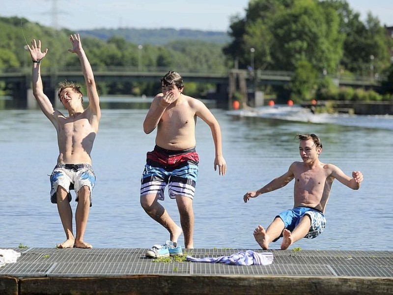 Ausflügler genießen die seit langem ersten schönen Tage des Sommers. Am Ruhrbogen in Bochum-Dahlhausen lassen sich die Jungs rücklings in die Ruhr fallen.