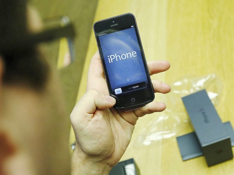 A customer opens his new Apple iPhone 5 during the launch, at the Apple Store in Covent Garden in London September 21, 2012.     REUTERS/Luke MacGregor    (BRITAIN - Tags: BUSINESS TELECOMS)