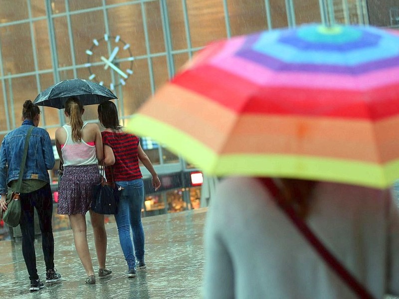 Reisende gehen am in Köln  durch den Regen zum Hauptbahnhof.