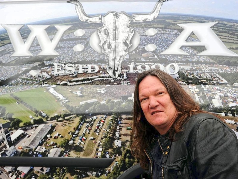 Thomas Jensen, Veranstalter des Wacken-Open-Air-Festivals, steht im schleswig-holsteinischen Wacken vor einem Bild des Festivalgeländes.