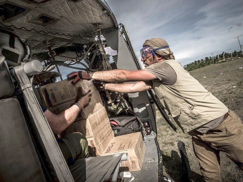 Katastrophenhelfer von ACF, einer Partnerorganisation der Kindernothilfe beladen einen Hubschrauber der Kanadischen Armee mit Nahrungspaketen. Die Notfallnahrung versorgt die Menschen für 14 Tage. Die Kanadische Armee fliegt die Hilfsgüter un unzugängliche Gebiete in den Bergen.  Die Katastrophenhelferin Lucile von ACF führt Angelika Böhling durch die Unglücksgebiete 28.11.2013 auf der Insel Panay - Phillippinen    Bild: Jakob Studnar