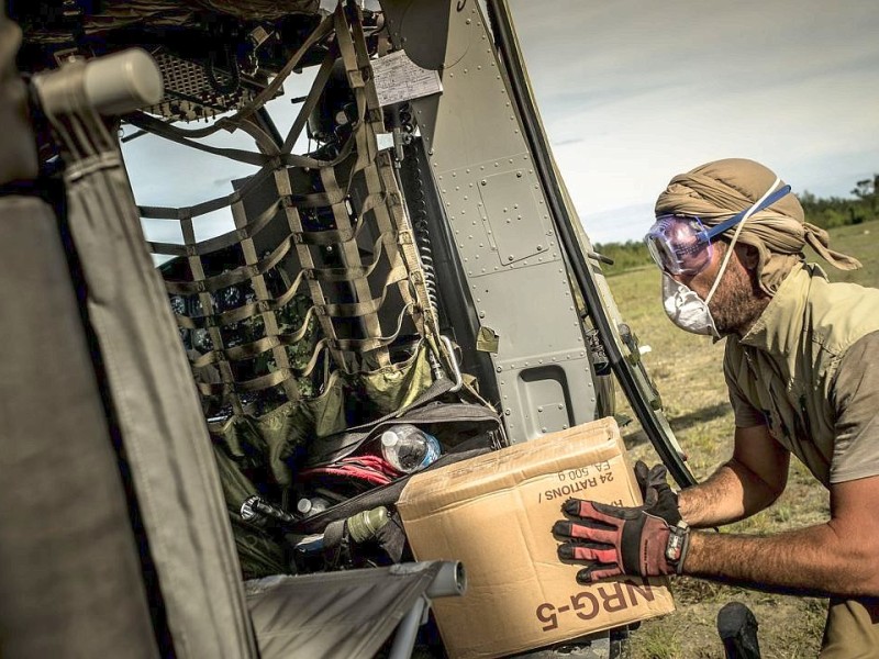 Katastrophenhelfer von ACF, einer Partnerorganisation der Kindernothilfe beladen einen Hubschrauber der Kanadischen Armee mit Nahrungspaketen. Die Notfallnahrung versorgt die Menschen für 14 Tage. Die Kanadische Armee fliegt die Hilfsgüter un unzugängliche Gebiete in den Bergen.  Die Katastrophenhelferin Lucile von ACF führt Angelika Böhling durch die Unglücksgebiete 28.11.2013 auf der Insel Panay - Phillippinen    Bild: Jakob Studnar