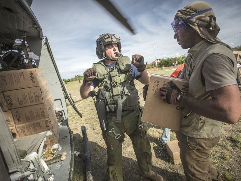 Katastrophenhelfer von ACF, einer Partnerorganisation der Kindernothilfe beladen einen Hubschrauber der Kanadischen Armee mit Nahrungspaketen. Die Notfallnahrung versorgt die Menschen für 14 Tage. Die Kanadische Armee fliegt die Hilfsgüter un unzugängliche Gebiete in den Bergen.  Die Katastrophenhelferin Lucile von ACF führt Angelika Böhling durch die Unglücksgebiete 28.11.2013 auf der Insel Panay - Phillippinen    Bild: Jakob Studnar