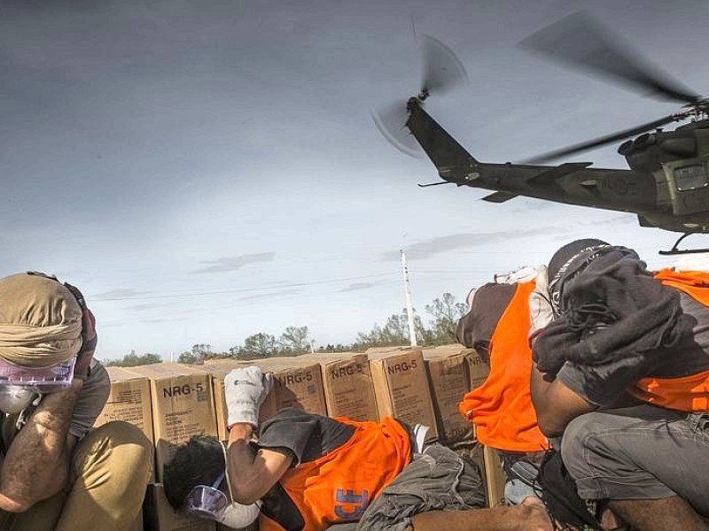 Katastrophenhelfer von ACF, einer Partnerorganisation der Kindernothilfe beladen einen Hubschrauber der Kanadischen Armee mit Nahrungspaketen. Die Notfallnahrung versorgt die Menschen für 14 Tage. Die Kanadische Armee fliegt die Hilfsgüter un unzugängliche Gebiete in den Bergen.  Die Katastrophenhelferin Lucile von ACF führt Angelika Böhling durch die Unglücksgebiete 28.11.2013 auf der Insel Panay - Phillippinen    Bild: Jakob Studnar