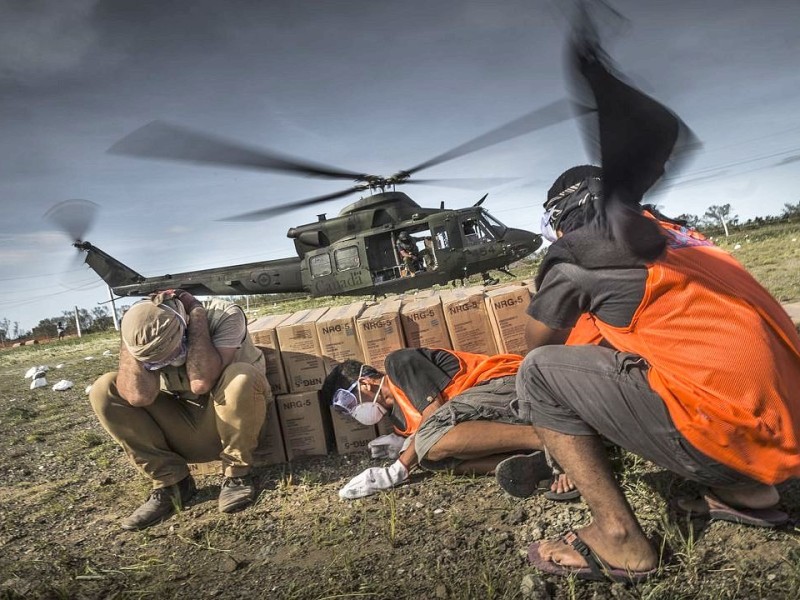 Katastrophenhelfer von ACF, einer Partnerorganisation der Kindernothilfe beladen einen Hubschrauber der Kanadischen Armee mit Nahrungspaketen. Die Notfallnahrung versorgt die Menschen für 14 Tage. Die Kanadische Armee fliegt die Hilfsgüter un unzugängliche Gebiete in den Bergen.  Die Katastrophenhelferin Lucile von ACF führt Angelika Böhling durch die Unglücksgebiete 28.11.2013 auf der Insel Panay - Phillippinen    Bild: Jakob Studnar