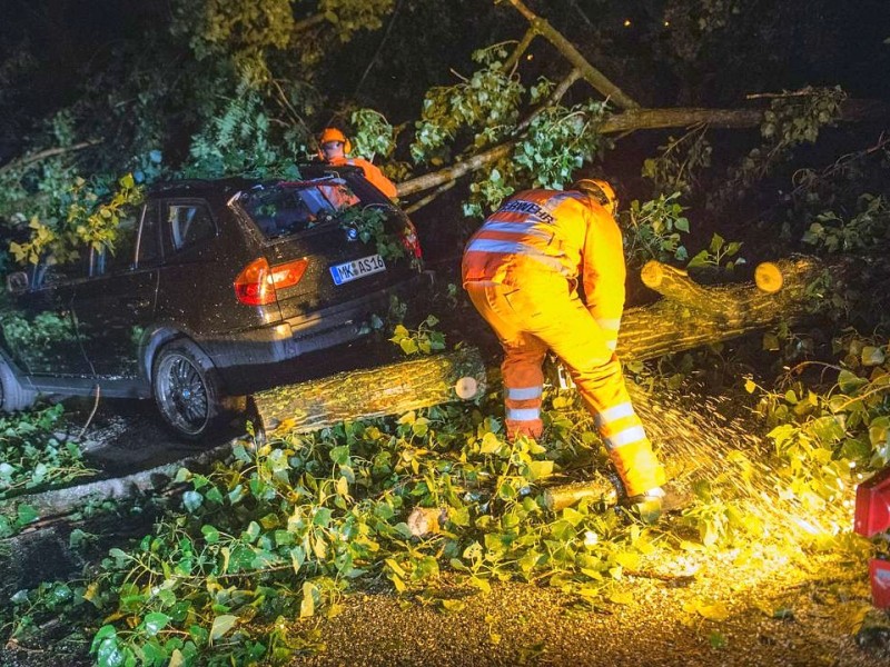 Feuerwehrleute mit Motorsägen arbeiten sich gleich nach dem Unwetter auf der A52 in Düsseldorf zu einem Auto vor...