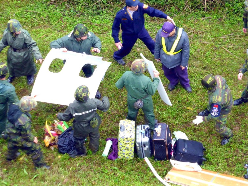 Helfer und Soldaten bergen ein Wrackteil aus dem Fluss.