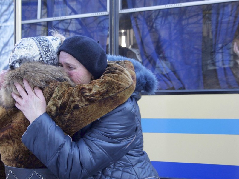 Zur Verabschiedung umarmen sich zwei Frauen. Der Bus...