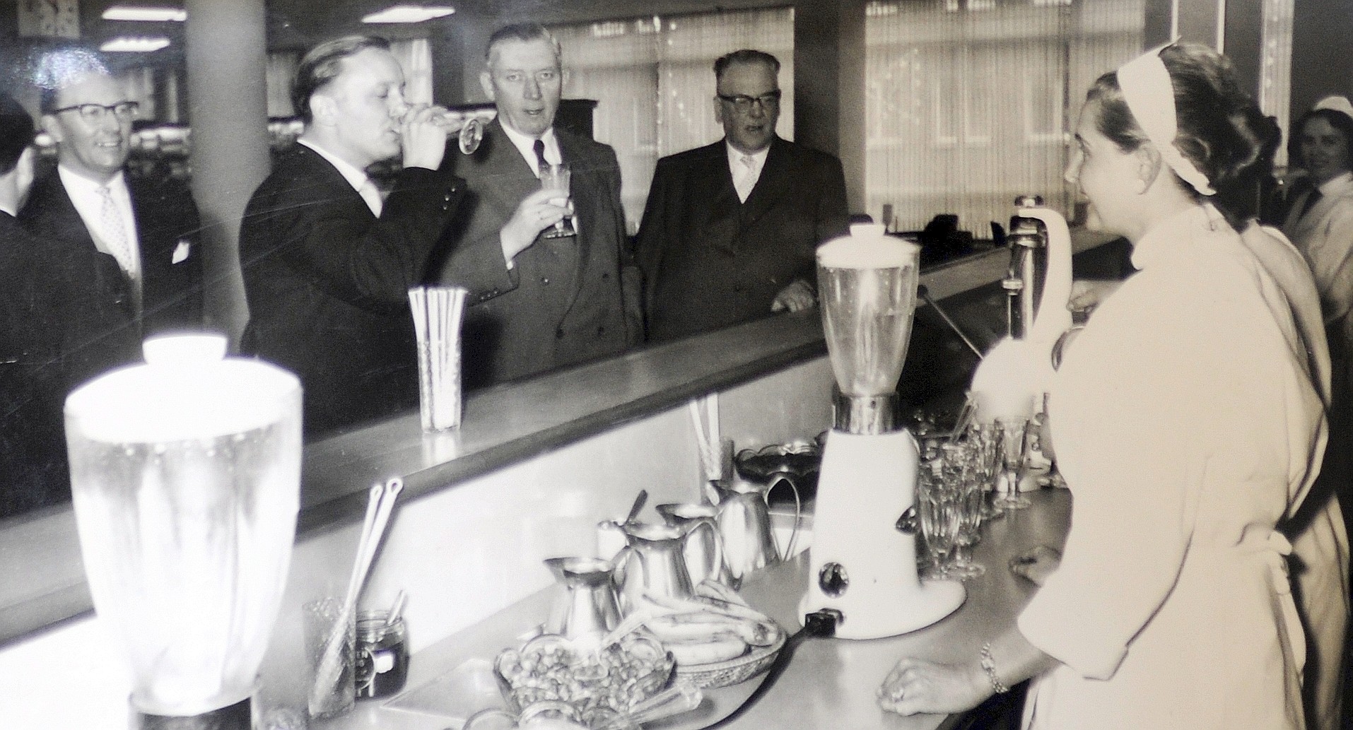 Zur Abwechslung mal an der Milchbar: Oberbürgermeister Ernst Wilczok und Oberstadtdirektor Dr. Kleffner (v.l.) probieren ein Mixgetränk im 1956 erweiterten Kaufhaus.