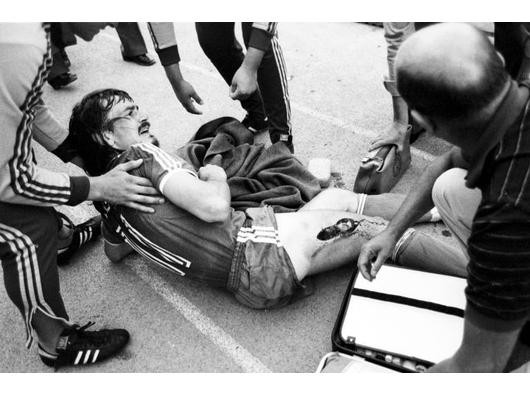 Erst auf der Tartanbahn wird Lienen behandelt, nach einem kleinen Handgemenge mit dem Gegner-Trainer Otto Rehhagel, auf den Lienen nach dem Spiel wie im Wahn zugestürmt ist. Foto: Imago