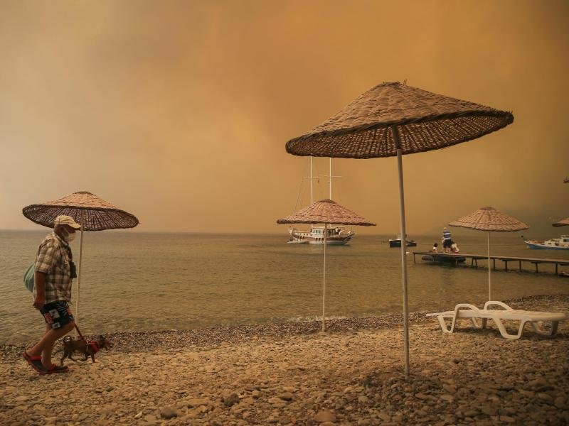 Ein Mann mit Hund am Strand in der Ferienregion Bodrum: In Teilen der Türkei toben heftige Brände.