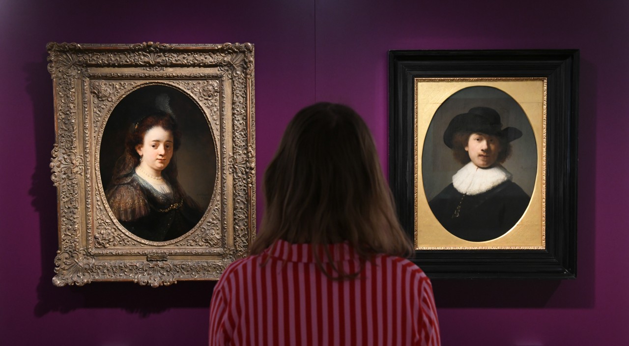 Eine Frau steht bei der Vorbesichtigung der neuen Sonderausstellung "Kassel... verliebt in Saskia" in Schloss Wilhelmshöhe zwischen dem "Porträt von Saskia Uylenburgh" (1636) des Malers Govert Flinck und dem Selbstbildnis von Rembrandt van Rijn (1632). 