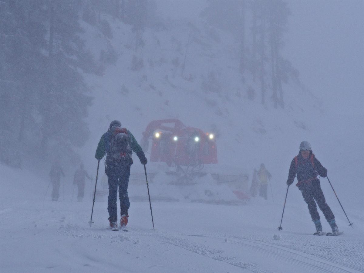 Zwei Skitourengeher und eine Pistenraupe sind im noch nicht geöffneten Skigebiet am Spitzingsee in Oberbayern unterwegs. Die Winterurlaubsregionen in den deutschen Alpen starten mit großem Handicap in den zweiten Corona-Winter. Die strengsten Corona-Vorschriften im deutschsprachigen Alpenraum lassen die Seilbahnbetreiber um die Existenz fürchten.