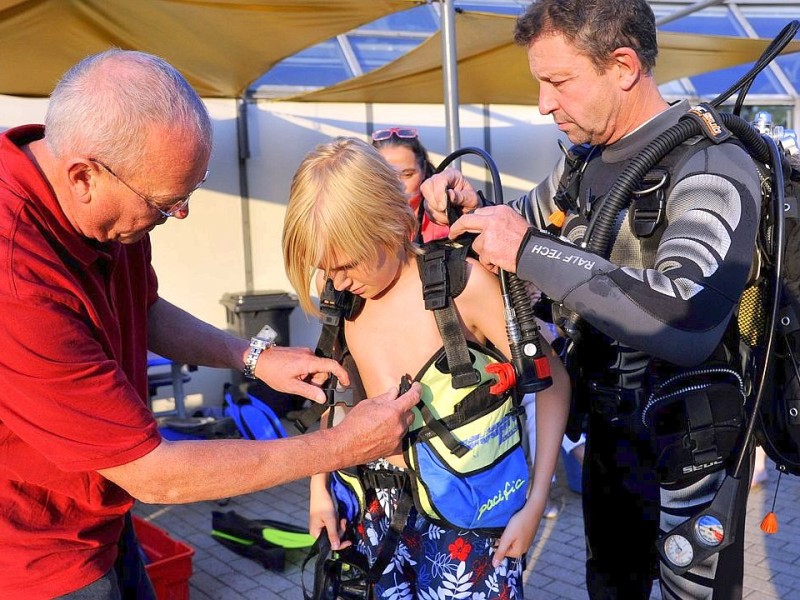 Schnuppertauchen für Kids bei den Tauchsportfreunden Herdecke im Freibad an der Hengsteyseestraße. Bild: Peter Granert (links) und Ernst Duhme (rechts) helfen Kevin (13, mitte) die schwere Ausrüstung für das Flaschentauchen anzulegen.Foto: Jürgen Theobald