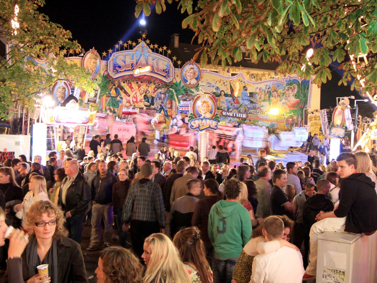 Auf der Haaner Kirmes in NRW tummeln sich Menschen vor einem Fahrgeschäft.