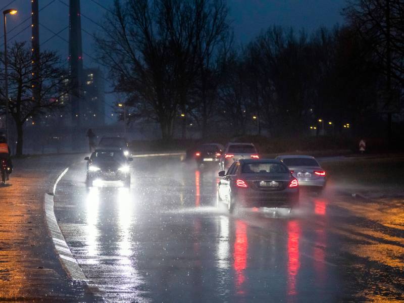 In Düsseldorf fahren Autos über eine regennasse Straße.