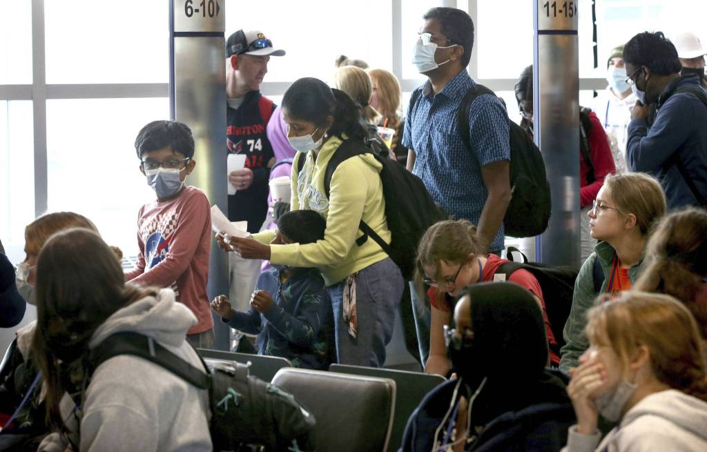 Mehrere Passagiere warten in einer Halle eines Flughafens.