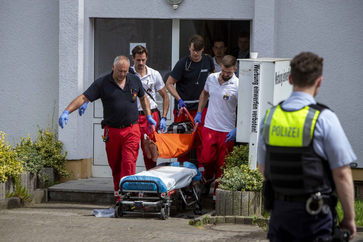 Rettungskräfte tragen verletzte Person aus Haus