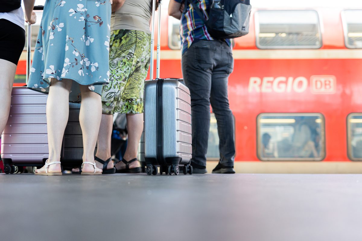 Fahrgäste warten mit ihrem Gepäck vor einem Regionalexpress der Deutschen Bahn in NRw