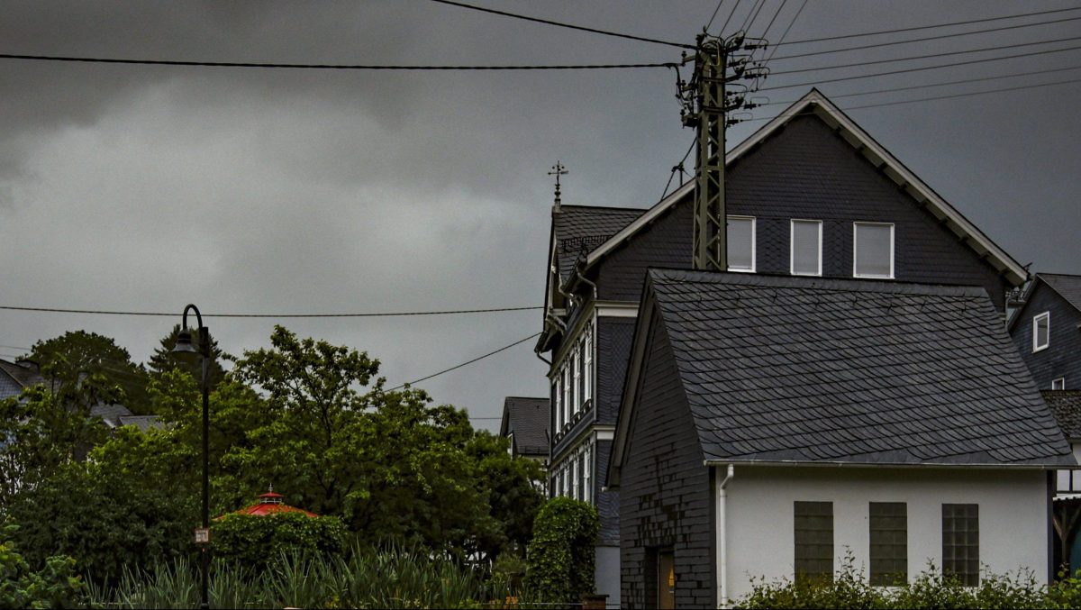 Dunkle Wolken am Himmel hinter Häusern und Bäumen