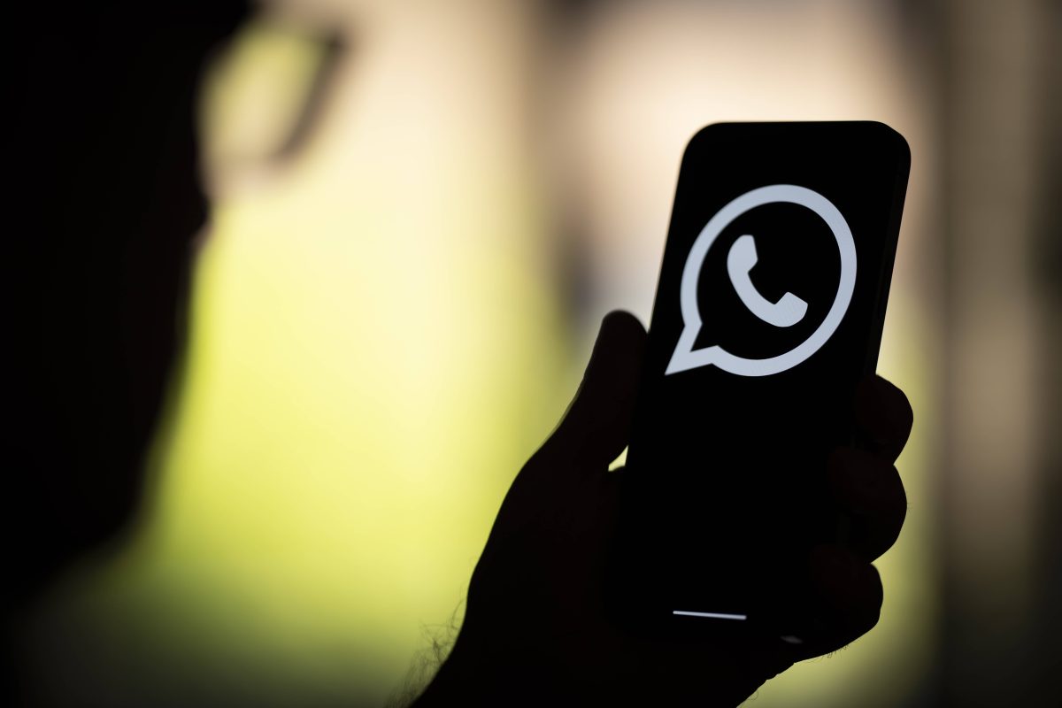 Mann schaut auf Whatsapp-Symbol auf Smartphone