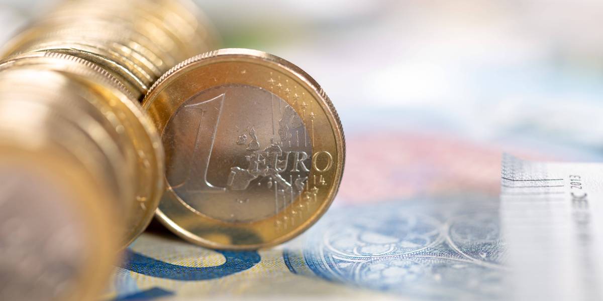 Eine 1-Euro-Münze steht senkrecht in einer Reihe von Münzen.