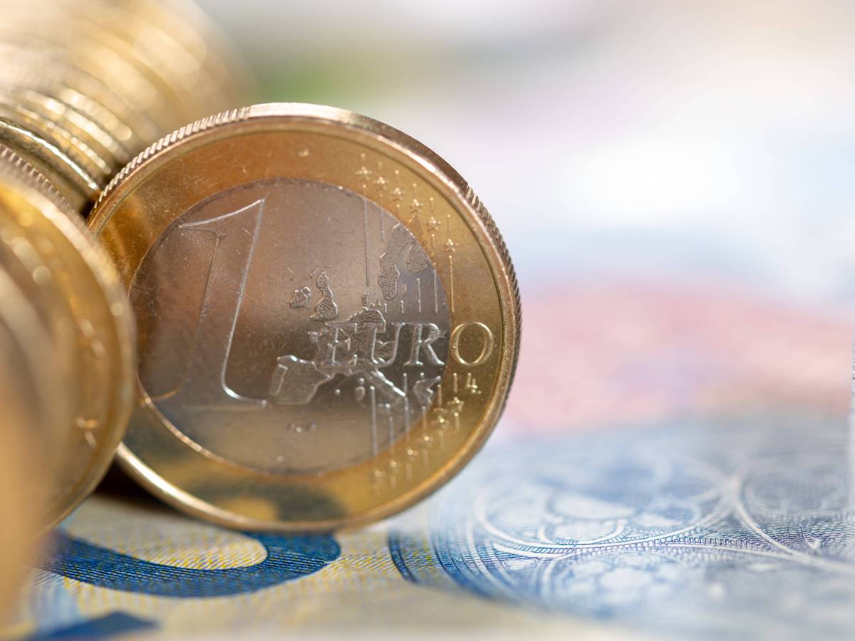 Eine 1-Euro-Münze steht senkrecht in einer Reihe von Münzen.