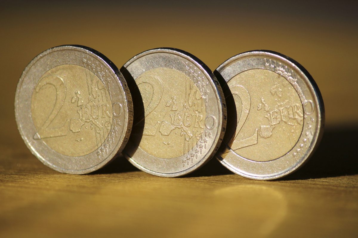 Drei 2-Euro-Münzen stehen auf ihrem Rand nebeneinander.