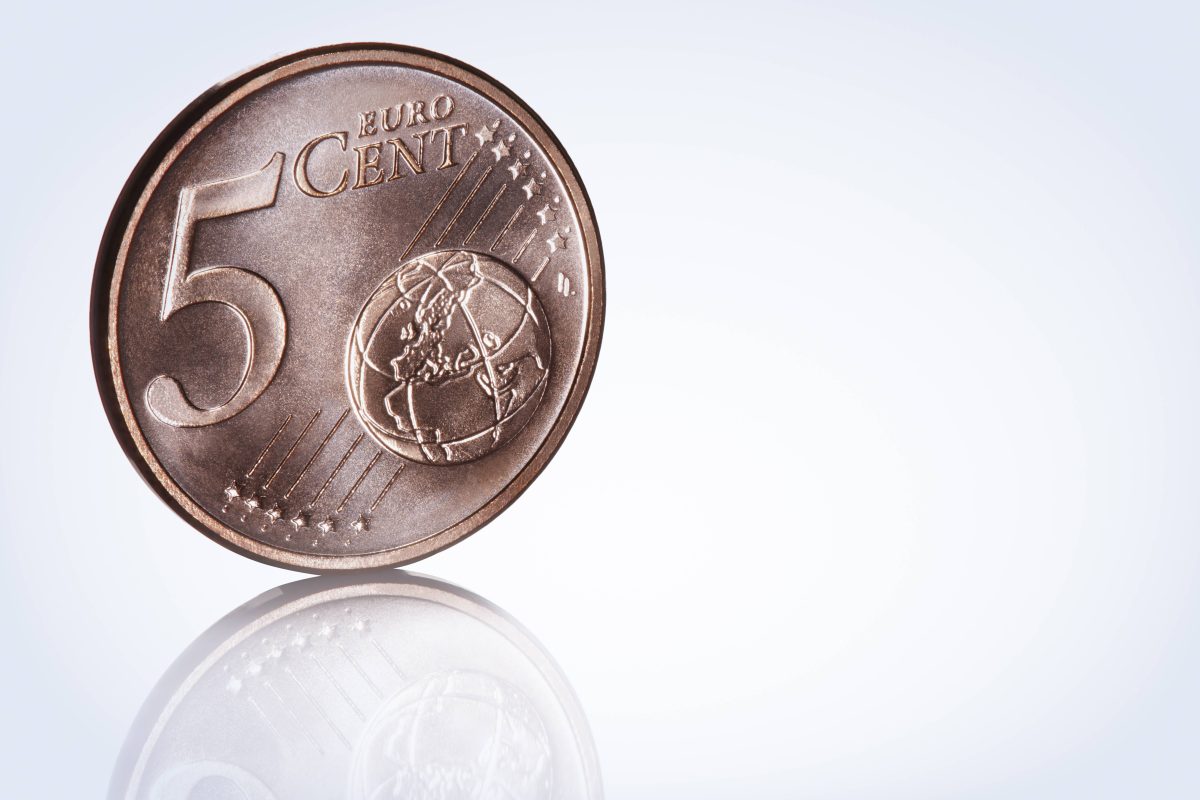 Eine 5-Cent-Münze steht senkrecht auf dem Boden.