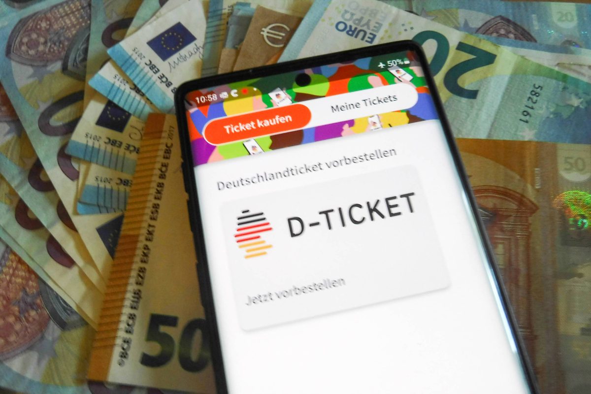 Deutschlandticket auf Handy, das auf Euro-Scheinen liegt