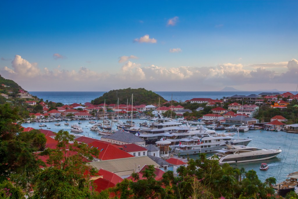 Im Hafen von Saint Barthélémy liegen Luxus-Yachten dicht an dicht. Der Blick schweift über Hafen zum Horizont und Meer. 